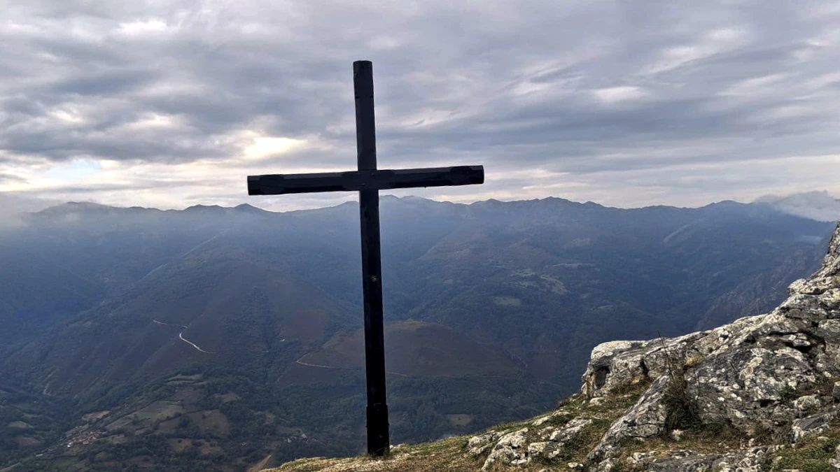 Cruz en la cima de la ermita del Alba con vistas panorámicas a las montañas de Asturias.